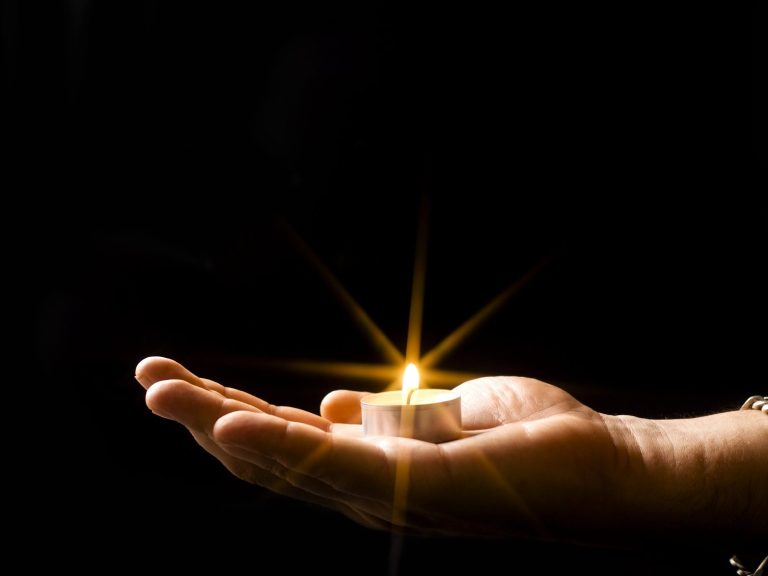 A hand holding a candle with a flame